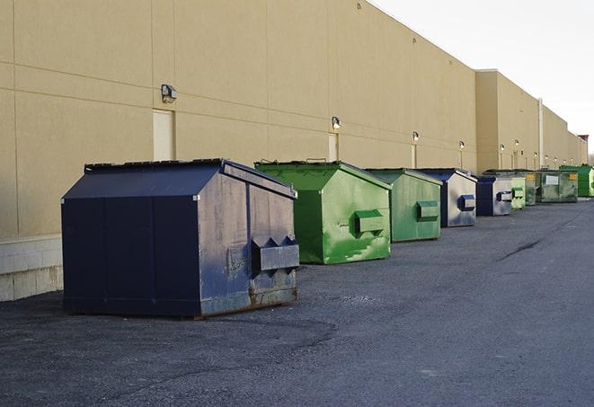 construction workers throw waste into a dumpster behind a building in Capron, IL